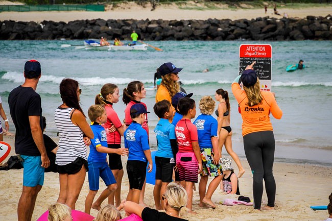 grupo de niños en la arena con una instructura de surf